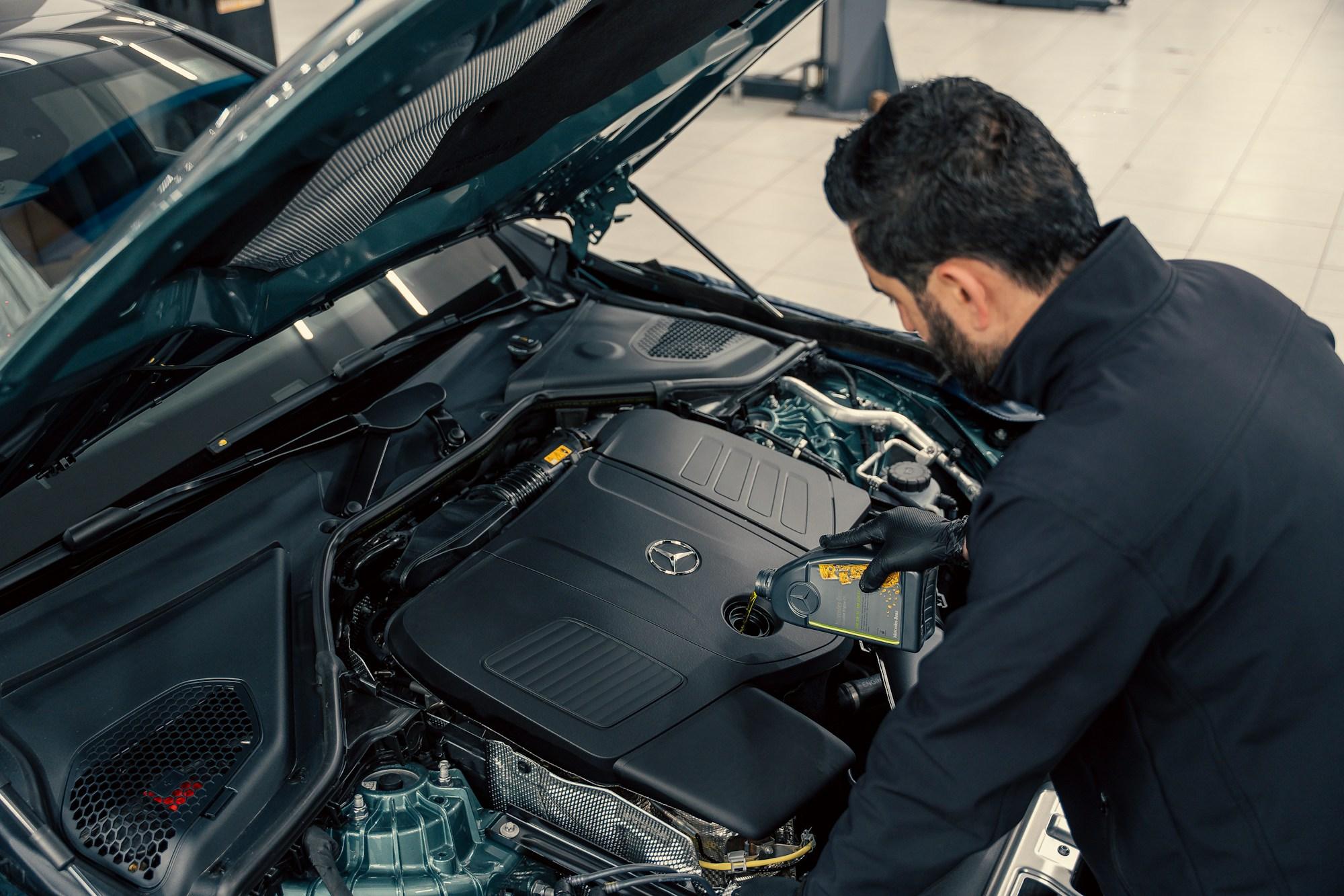 Mechanic leaning into an open engine bay during a service