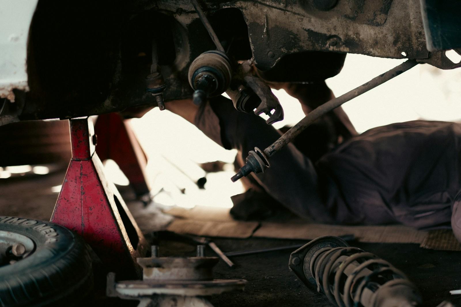 Mechanic underneath a vehicle working on the drivetrain
