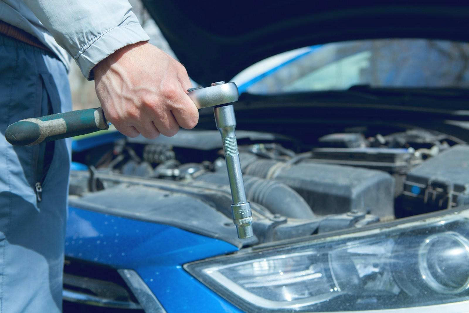 Mechanic using a socket wrench on a car engine